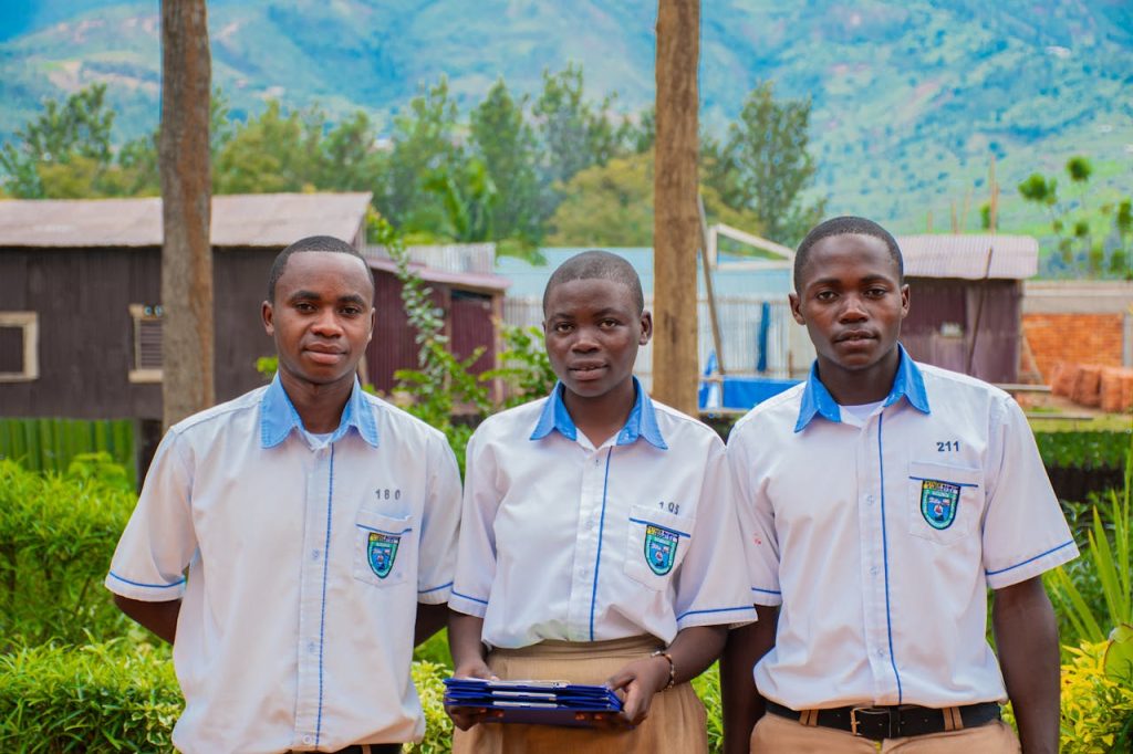 pexels-photo-32037736 Three students in uniforms standing outdoors with a scenic mountain background.